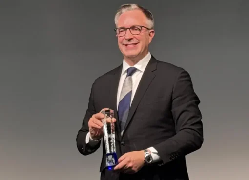 Academy CEO Bill Kramer speaking at an event in Tokyo, with a screen behind him.
