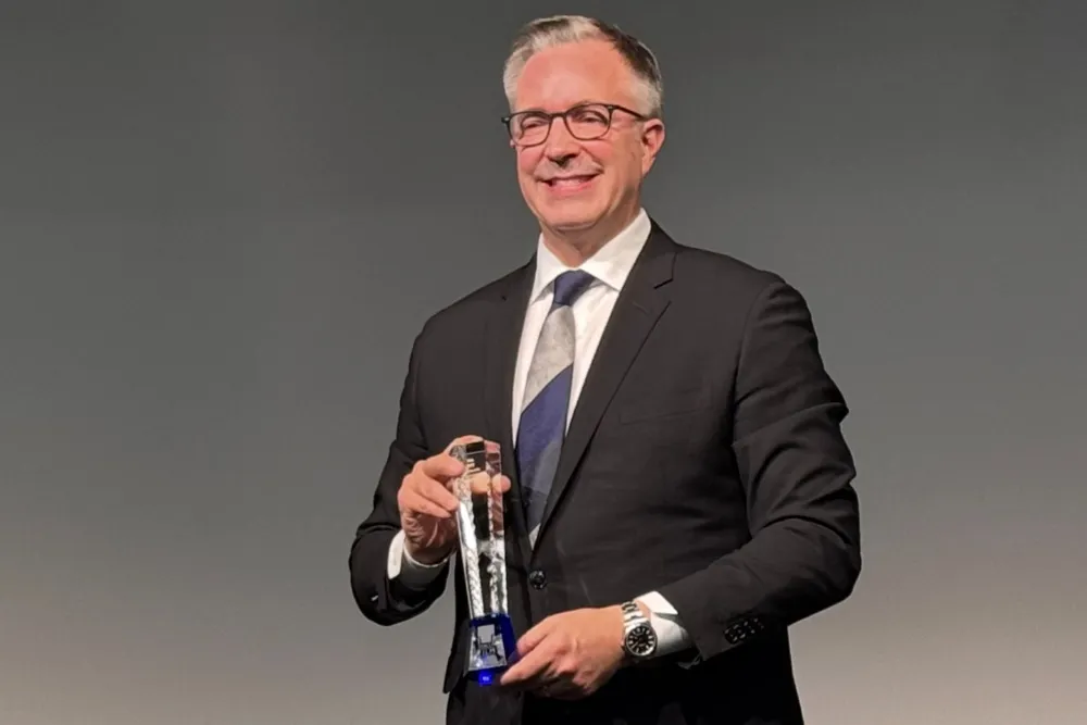 Academy CEO Bill Kramer speaking at an event in Tokyo, with a screen behind him.