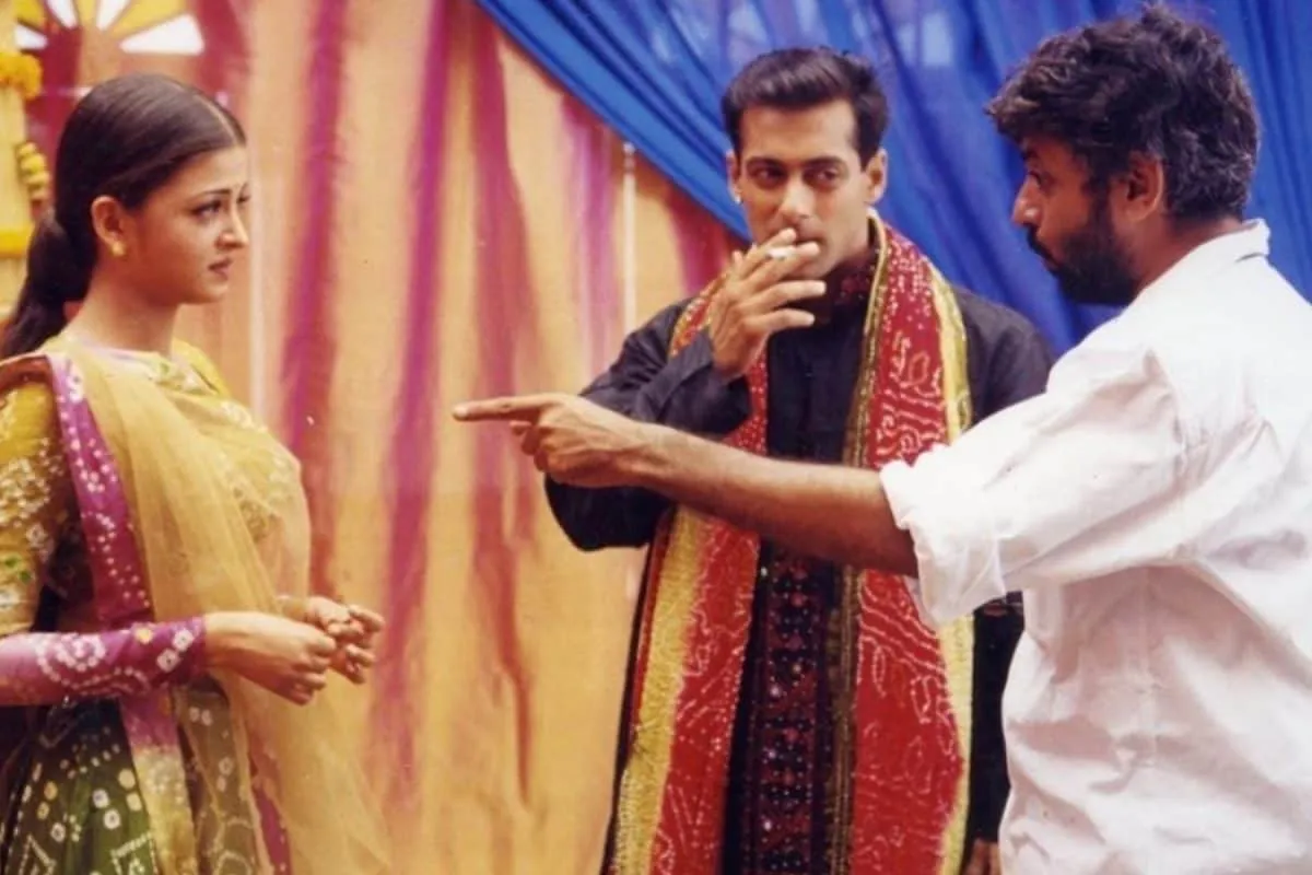 Sanjay Leela Bhansali looking intense, with faint images of Salman Khan and Aishwarya Rai in the background.