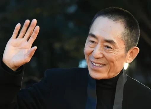 Chinese director Zhang Yimou at the Busan International Film Festival, speaking into a microphone.