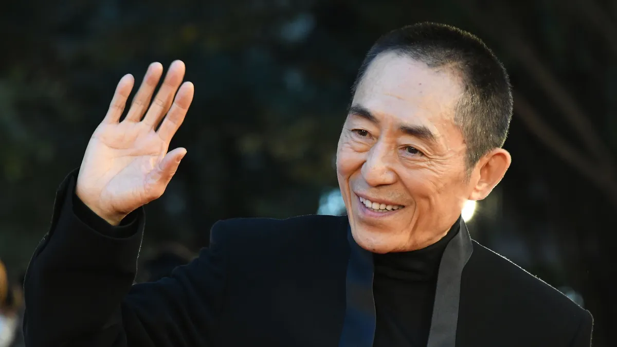 Chinese director Zhang Yimou at the Busan International Film Festival, speaking into a microphone.