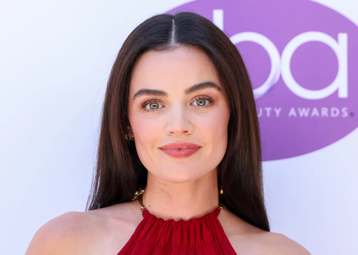 Lucy Hale looking thoughtful, perhaps in a sophisticated, detective-style outfit.