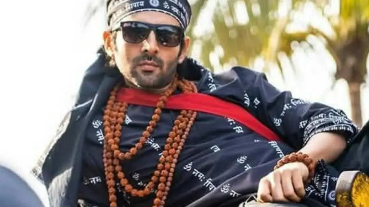 Kartik Aaryan dressed as Rooh Baba from Bhool Bhulaiyaa, striking a pose with a mysterious smile and flowing scarf.