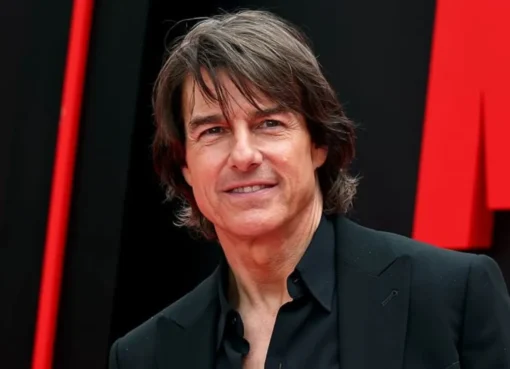 Tom Cruise smiling broadly at a red carpet movie premiere.